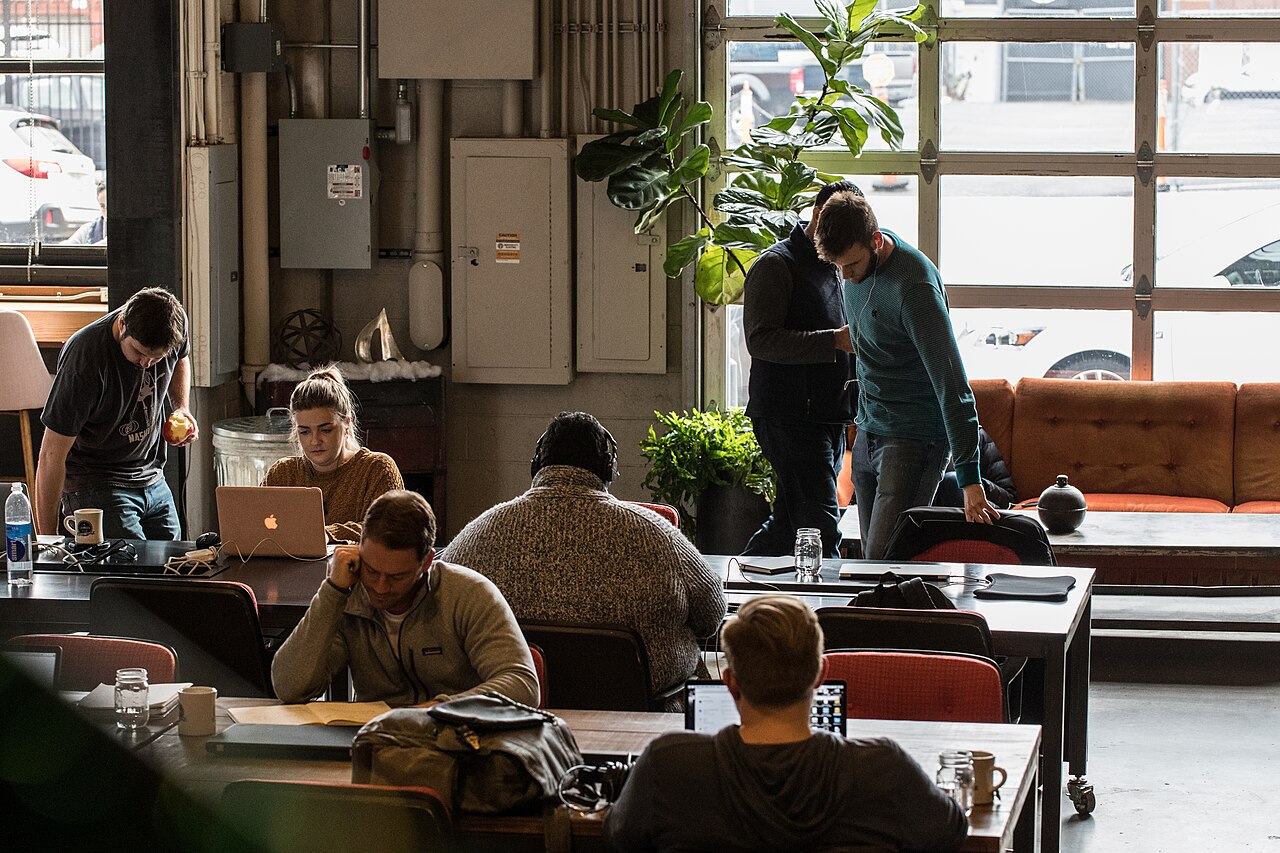 Profissionais trabalham em mesas compartilhadas de um coworking
